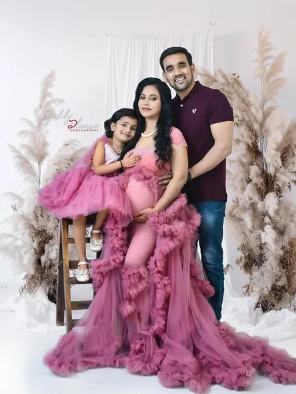 A complete family portrait during a maternity session. The mother and daughter are in beautiful pink gowns, joined by the father for a picture perfect family photo.