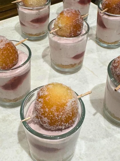 Strawberry mousse dessert cups topped with a sugar-dusted doughnut hole. This playful and delicious combination is a creative twist on dessert shooters.