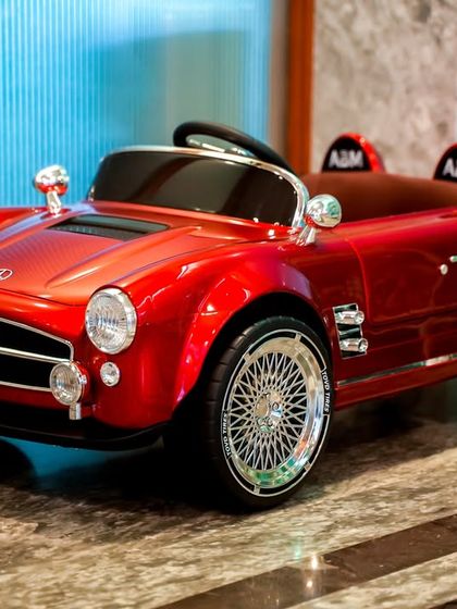A stylish, bright red vintage-style electric car for the youngest guests to enjoy a supervised drive around the party area.