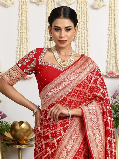 A close-up portrait of the model wearing the red saree, showcasing the intricate details of the blouse and the rich weave of the saree.
