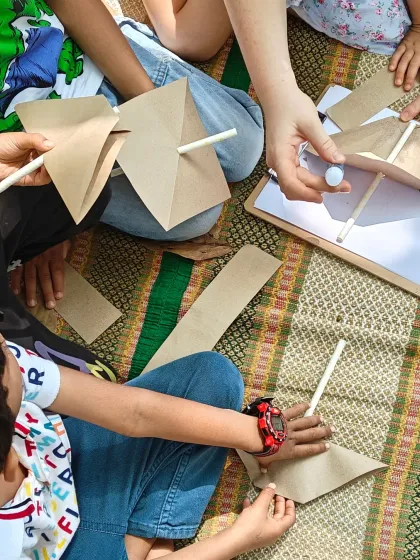 Children work together to create paper pinwheels during a craft session. This simple toy is not only fun to make but also teaches a basic principle of how wind works, blending art with science.