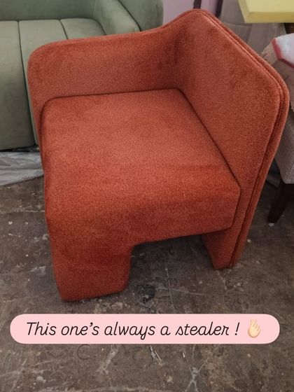 This modern accent chair in a burnt orange fabric is always a stealer. Its unique, geometric form and wrap-around back make it a comfortable and stylish addition to any living space.