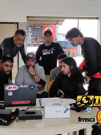 A group of riders intently studying the data on screen. The camaraderie and shared learning experience are a huge part of our track school.