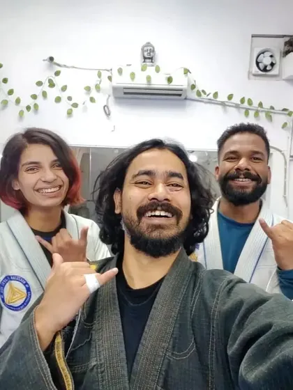 Two students and their coach after a Gi class, highlighting the supportive training environment.