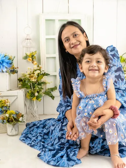 A beautiful mother-daughter portrait taken during a first birthday shoot. The matching blue tones and floral set create a lovely, cohesive image.