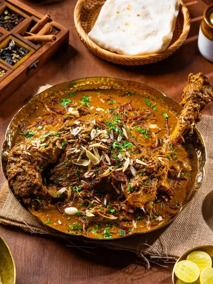 A festive and rich dish of Nalli Nihari. The overhead shot showcases the tender meat and garnish of fried onions and nuts.