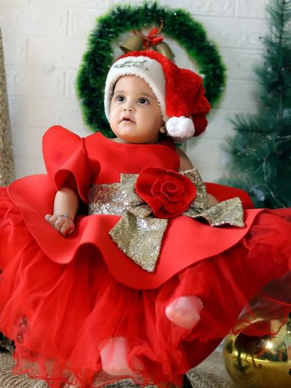A little girl in a Santa hat and a gorgeous red dress, ready for her holiday portrait in our Christmas-themed studio.