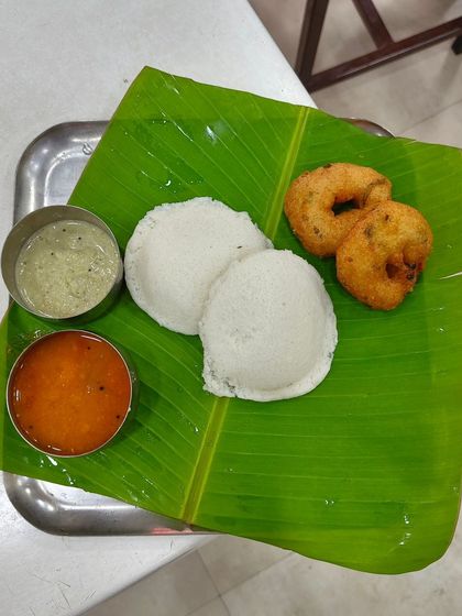A customer's view of our classic Idli Vada breakfast. Two perfectly soft idlis, two crispy vadas, and our signature sambar and chutney, all served on a traditional banana leaf.