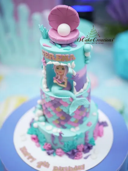 A closer look at the three-tier mermaid cake, showcasing the detailed scales and the edible oyster with a pearl on top.