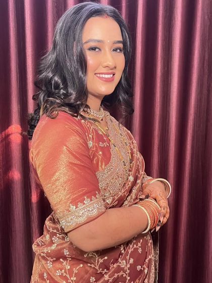 A happy, smiling portrait of the bride in her reception saree. The makeup is designed to enhance her features and give her a radiant glow.