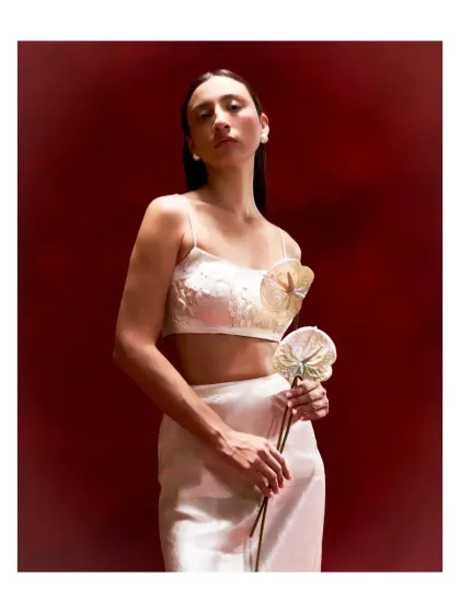A modern and minimal white bustier with sculptural floral details. This piece is perfect for pairing with a high-waisted skirt or trousers for a contemporary festive look.