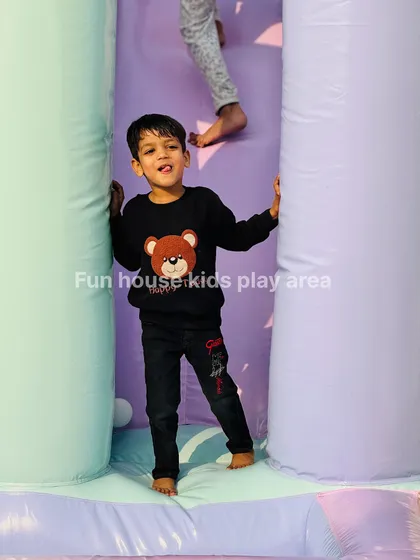 A child peeking out from between the soft pillars of our pastel bouncy, ready for a game of hide-and-seek.