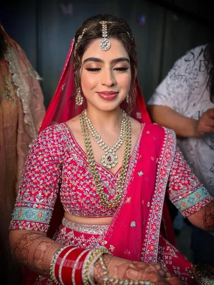 A timeless look for Jasleen's wedding day. The makeup features a soft, romantic eye and a neutral lip to complement her vibrant pink lehenga.