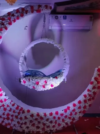 This image shows a naming ceremony decoration set up at home. It proves that you don't need a large hall to have my signature floral moon cradle and a beautifully decorated space for your baby's celebration.