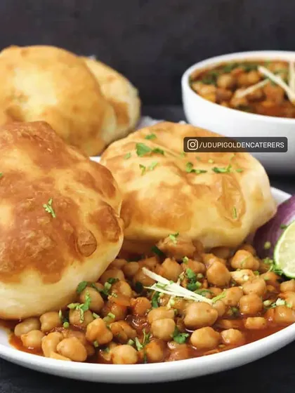 To show our menu's versatility, we offer North Indian classics like Chole Bhatura. This dish features fluffy, deep-fried bhatura bread served with a hearty and spicy chickpea curry, garnished with fresh onions and a slice of lime.