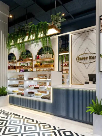 The counter and display area of this modern bakery feature a mix of materials, including fluted panels, marble, and hanging greenery. The design focuses on creating an attractive product showcase that is both functional for staff and inviting for customers.