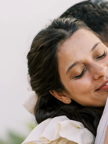 A tight close-up on the mother's face as she embraces her partner. This shot is all about the feeling of safety, love, and contentment in his arms.