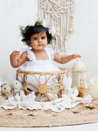 A full view of the angelic boho setup, with the baby girl reaching out from her basket.