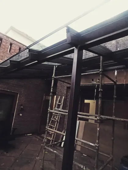 A work-in-progress view of a glass room installation. The scaffolding provides safe access for our team as they assemble the prefabricated components against the existing brick building.