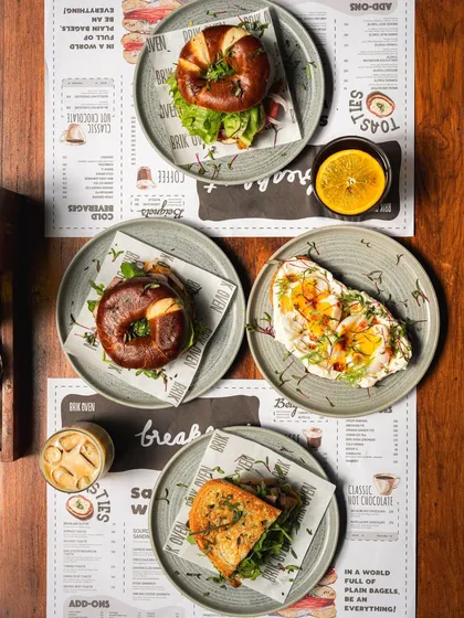 A flat lay of our breakfast menu, featuring a variety of sandwiches, toasts, and coffees.