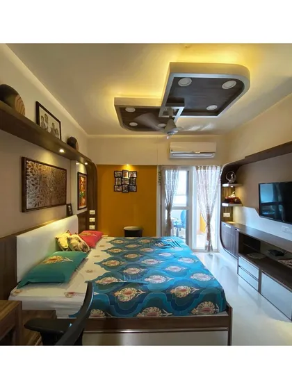 This perspective shows the full length of the room, including the custom-built TV unit that mirrors the curved design elements of the headboard, ensuring a cohesive aesthetic.