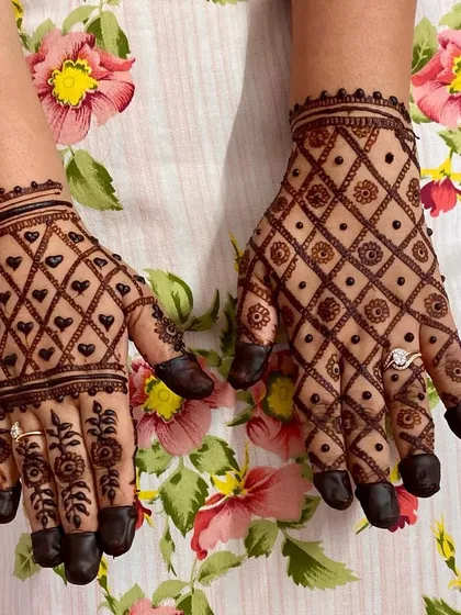A classic jaal (net) pattern on the back of the hands. One hand features a diamond-shaped net with hearts, while the other has a floral net, both with full fingertips.
