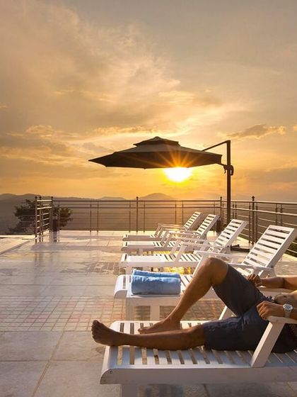 A guest relaxing by the pool at sunset at Coorg Cliffs Resort. The golden light and expansive views make for a truly magical experience.