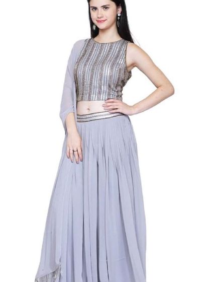 A chic grey lehenga set featuring a sleeveless crop top with vertical silver sequin work. The matching pleated skirt and simple dupatta create a modern and understated look for an evening event.