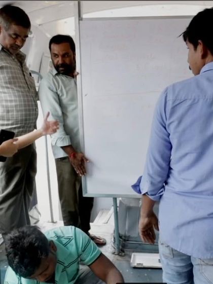 The project lead discusses the installation of a whiteboard inside the bus. This collaborative effort brought together designers, foundations, and city officials to create a unique educational tool for the community.