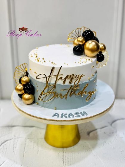 A simple yet elegant cake for a birthday boy. This design features a cool grey-blue and white color scheme with modern black and gold sphere decorations.