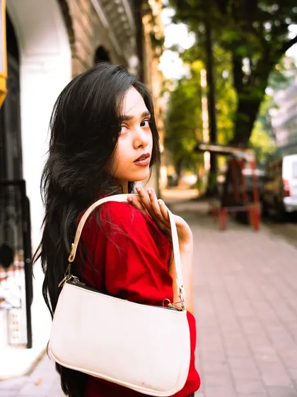 A classic over-the-shoulder pose that is both engaging and stylish, showcasing the handbag as a key accessory.