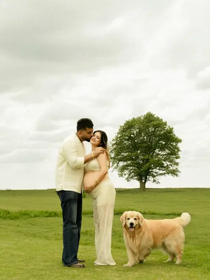 A beautiful family portrait in a wide-open field, with their golden retriever standing proudly by their side. Yes, pets are always welcome.