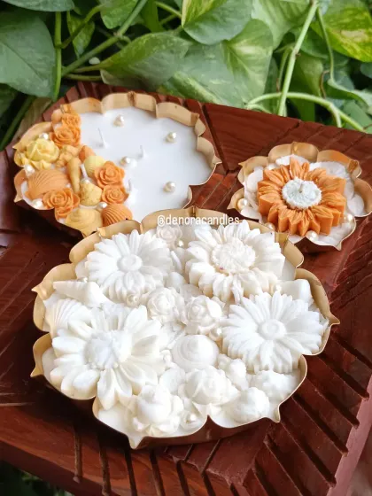 Here you can see the intricate detail and variety within my urli candle collection. Each piece is handcrafted with different floral arrangements, from delicate white daisies to vibrant orange blossoms, making each candle a unique work of art.