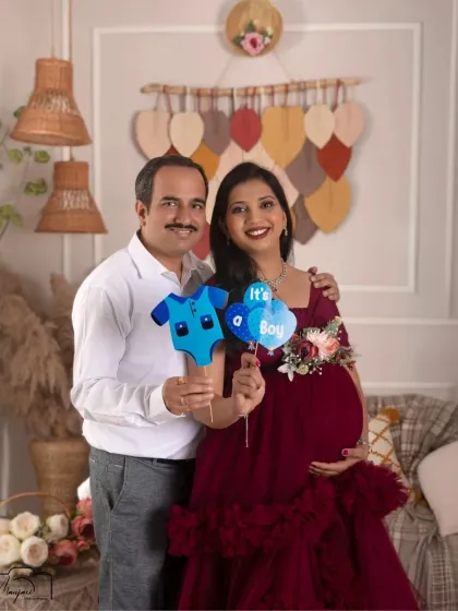 A sweet couple's portrait in the boho setup, announcing they're expecting a boy. The deep red gown is a beautiful, bold choice.