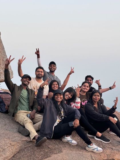 A group of friends posing together on the rocks of Uttari Betta, celebrating a successful sunrise hike.