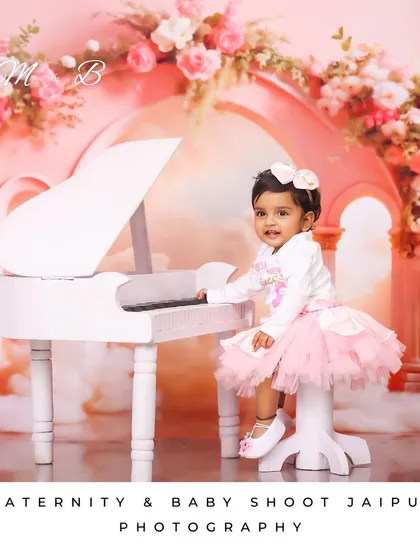 A slightly different angle of my little pianist. The pink floral arch and soft lighting create a heavenly atmosphere for this princess-themed baby portrait.