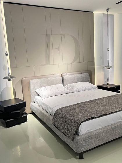 A tranquil and sophisticated bedroom. The minimalist bed in a light grey fabric is flanked by unique stacked-box bedside tables and modern chrome pendant lights, creating a clean and contemporary aesthetic.