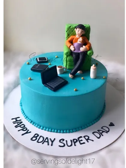 A custom cake for a "Super Dad" who juggles work and fatherhood. The fondant toppers show him working on his laptop while holding his baby.