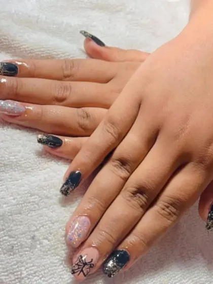 A darker, more intricate design. This set combines black and pink glitter nails with a hand-painted butterfly wing or web design for a unique, edgy look.