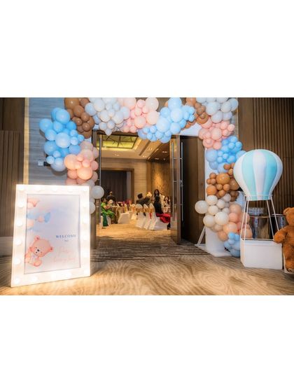 A wider shot of the entrance, showing how the balloon arch frames the doorway, leading guests into the decorated event space. A hot air balloon prop adds to the whimsical theme.