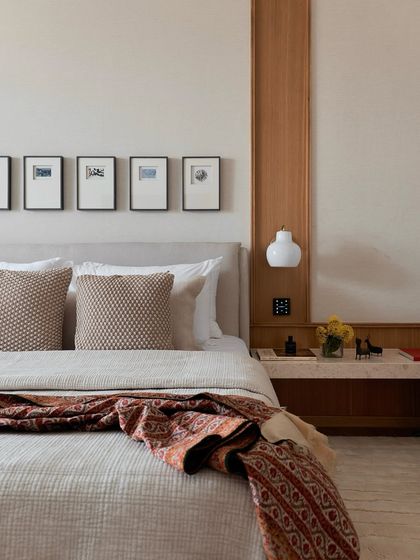 The master bedroom in the NG Penthouse is a study in simple, timeless elegance. A custom wood-panelled wall integrates the bedside lighting, while a vintage textile adds a touch of color and pattern to the serene setting.