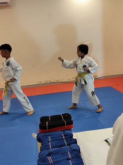 Two young students practice their fundamental stances and punches during a belt grading exam.