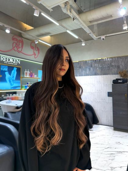 This vibrant balayage look was created using Redken color to achieve a brilliant, high shine finish. The warm tones blend seamlessly from the darker roots, creating a bold and beautiful style.