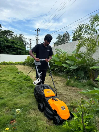 Lawn maintenance is a crucial part of our service. Here, a team member uses an electric lawnmower to keep the grass at a perfect height, ensuring a neat and healthy lawn for this residential project.