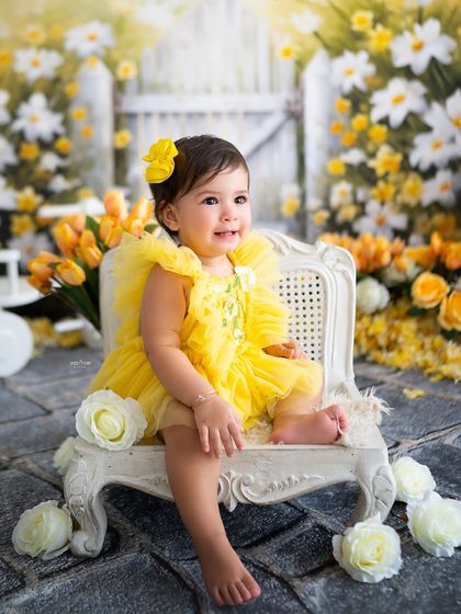 A happy smile from this little one, sitting among the yellow flowers for her first birthday shoot.