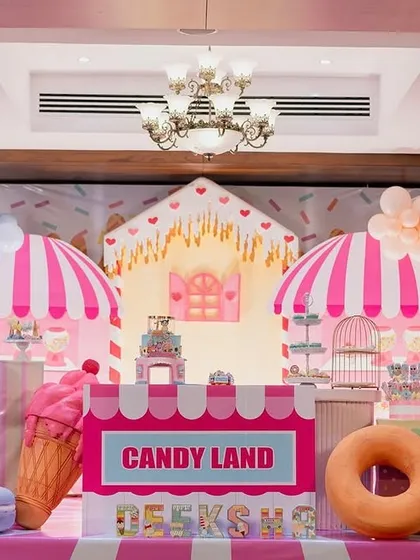 Welcome to Candyland. This party features giant lollipop and donut props, a candy-striped counter, and pastel balloon arrangements to create a sweet and whimsical world for a first birthday celebration.
