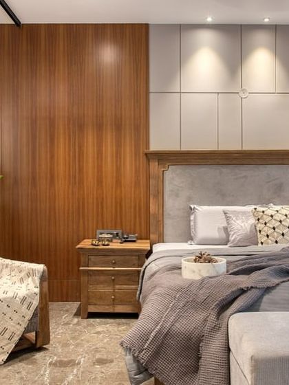 This bedroom at our East Punjabi Bagh project features a rustic-modern aesthetic, with a solid wood bed, a paneled accent wall, and a cozy armchair.