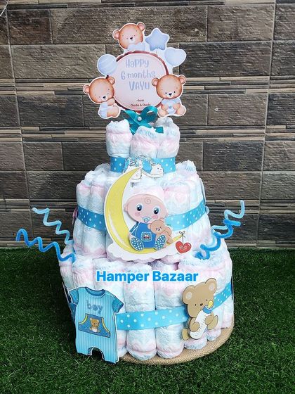 A two-tiered diaper cake celebrating a baby's 6-month milestone, decorated in a blue teddy bear theme.