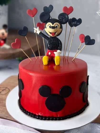 A classic Mickey Mouse cake in his signature red and black colors. The design is decorated with hearts and a full 3D Mickey figure, perfect for a Disney fan.