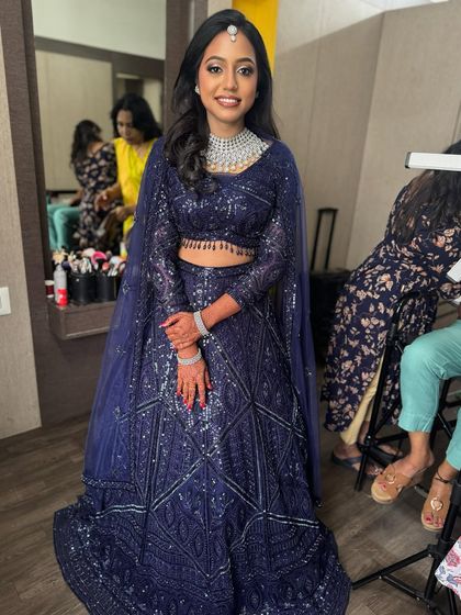 A full-length shot of Dr. Akshara, showcasing her magnificent navy blue lehenga and the complete makeup and hair look. She looks every bit the modern, glamorous bride.